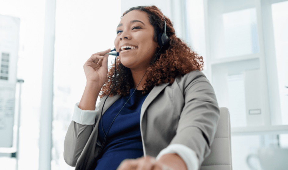 Woman wearing a headset and smiling in an office setting.