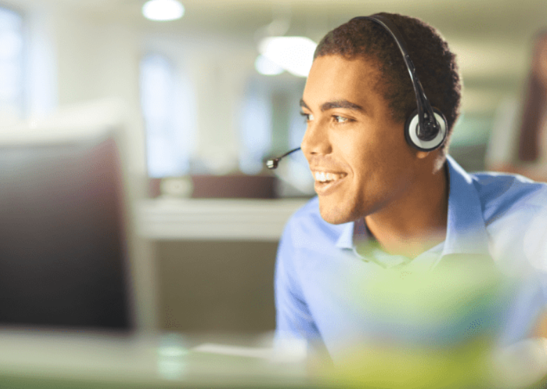 Man wearing a headset and smiling in an office setting.